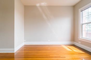 A room with wooden floors and a window letting in sunlight.